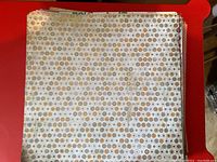 Top view of stack of scrapbooking paper showing circular pattern in beige and brown tones.