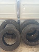 Four Bridgestone Insignia tires leaning against a garage door, showing general condition and quantity.