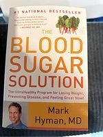 Front cover view of one book titled "The Blood Sugar Solution" by Mark Hyman, MD showing author image and beetroot illustration.