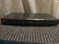 Front view of black Sony Blu-ray player showing branding and Blu-ray logo.