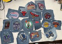 Image shows 16 individual jean patches with embroidered NBA team logos arranged on a flat surface. Teams include Chicago Bulls, Denver Nuggets, Brooklyn Nets, Los Angeles Clippers, Atlanta Hawks, Toronto Raptors, Portland Trail Blazers, Sacramento Kings, Boston Celtics, NBA logo, Los Angeles Lakers, New York Knicks, Milwaukee Bucks, Dallas Mavericks, Indiana Pacers, and Orlando Magic.