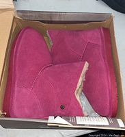 Top view of the pair of pink Bearpaw kids boots in an open box showing the suede and shearling interior.