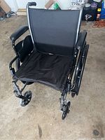 Front view of the black manual wheelchair showing fabric seat and backrest.