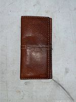 Closed brown leather wallet with visible texture and stitching, Fossil logo embossed on lower right corner
