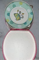 Photo showing stack of vintage plates with green polka dot rims and central cartoon figure.