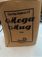 Cardboard box showing 'Mega Mug 28 oz' branding and slogan