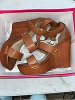 A pair of brown women's wedge sandals with ankle straps and stud detailing, size 10 by Shoe Dazzle.