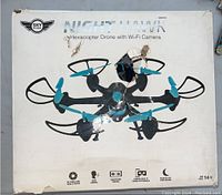 Front view of the original box depicting the Sky Rider Night Hawk Hexacopter Drone with Wi-Fi Camera in black and blue, with visible tears and damage to packaging.