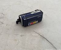 Closed blue Sony Handycam camcorder showing top and side with control buttons and zoom lever. Labels indicate 60x digital zoom and 4GB capacity.