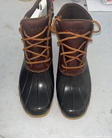 Front top view of the boots showing brown leather uppers with laces and waterproof black rubber soles.