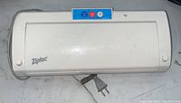 White Ziploc vacuum sealer device with visible power cord and control buttons.
