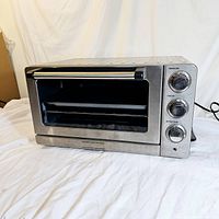 Front and slightly angled view of Cuisinart convection toaster oven broiler showing stainless steel body, black handle, and control knobs.
