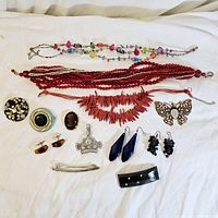 Photo showing the entire lot with necklaces, brooches, earrings, cufflinks and bracelets arranged on white fabric.