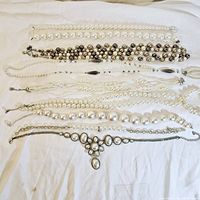Top down view showing all pearl necklaces and the statement bracelet arranged flat on white cloth.