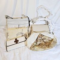 Lot of five white vintage purses and handbags, arranged on white fabric background, seen from above.