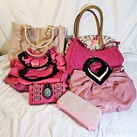 Photo showing seven vintage purses and handbags in shades of pink and beige arranged on a white backdrop.
