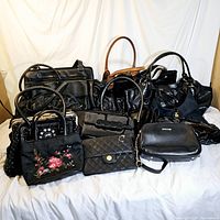 Wide group shot of 12 vintage skirts and handbags varied styles and shapes laid on white sheet