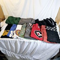 Folded various colored and printed men’s T-shirts and polos laid out on a white cloth background.