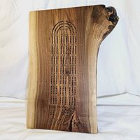 Front view of large live edge walnut cribbage board with engraved cribbage scoring holes and natural wood grain.