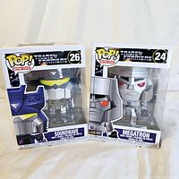 Photo showing both Funko Pop Transformers figures Megatron and Soundwave in their original sealed boxes from front.