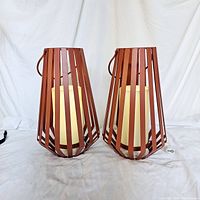 Pair of brown metal slat candle holders with ivory LED battery candles inside, front angle view.