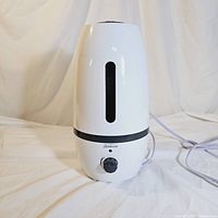White Sunbeam ultrasonic humidifier front view showing water level window, control knob, and power indicator light. Electric cord visible.