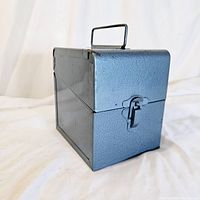 Angle view showing side and top of the vintage Logan metal storage container with handle and latch.