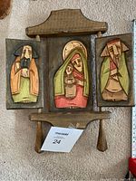 Front view of the wooden wall carving showing Mary and baby Jesus central panel with two side panels, all carved and painted.