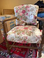 Front view of wooden framed accent arm chair with floral upholstery, displaying overall structure and floral print fabric.