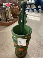 Front view of the painted decorative wooden butter churn showing floral designs and attached plunger with rounded handle.