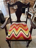 Front view photo of wooden armchair showing painted frame and colorful zigzag upholstered seat