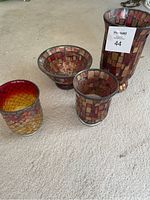 Photo showing the four glass items arranged: one large vase, two candleholders, and one bowl, all featuring mosaic square patterned glass.