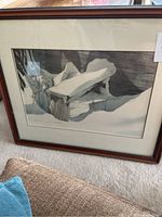 Framed print of a snow-covered wooden bench under glass in a wooden frame.