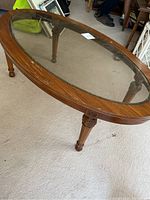 Full view of oval wood and glass coffee table showing overall shape and glass inset top.