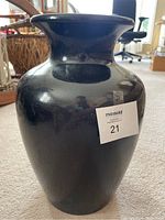 Front view of the large brown-black glazed ceramic vase with wide flared lip. Sticker label on body.