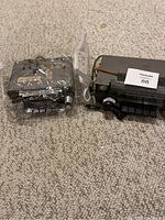 Two vintage car radios placed side by side on carpet, showing metal housings and wiring on one radio.