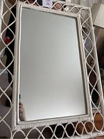 Full view of rectangular mirror with white wicker frame and woven openwork design.