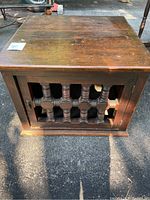 Front view of the carved wood accent table showing the door with decorative wooden spindles, knob, and base details. Wood surface shows wear and scratches.