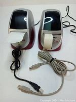 Two Dymo LabelWriter 330 Turbo label printers side by side, both with cables and labels emerging.