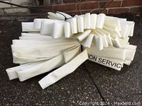 Photo of one folded and bundled white fire hose with visible folds and some black printed text.