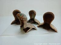 Four antique Victorian era clawfoot bathtub legs made of cast iron, displayed side by side on a white surface. Each leg has visible rust and aged wear.