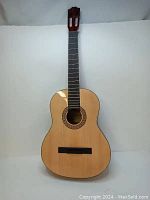 Full front view of the natural wood acoustic classical guitar body showing soundhole, bridge, and fingerboard without strings or hardware.