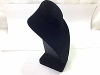 Front right angle view of the black velvet necklace display stand showing its elegant curved shape and solid base.