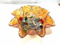Top/front view of the iridescent marigold Fenton bowl filled with glass marbles showing ruffled edge and fish scale pattern
