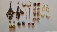 Full overview of all 12 pairs of vintage earrings arranged on white background