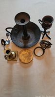Full lot overview showing all items including chamberstick, brass candlestick, round box, spoons, and lamp clip holder