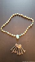 Full image of necklace laid out with the large turquoise scarab centerpiece and the seven vintage metal keys underneath.