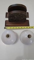 Pair of carved wood bookends and two milk white glass globes with measuring tape showing size of globes.