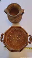 Overhead view of Mediterranean style vase and octagonal antique pottery colander with handles and drainage holes alongside measuring tape
