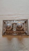 Top view of ornate rectangular silver inkwell stand with two circular lids and intricate floral engraving